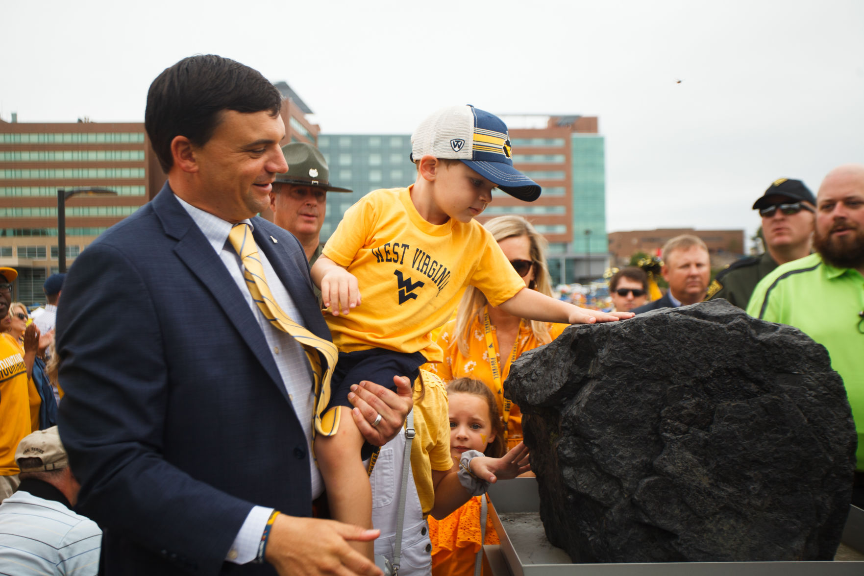 As West Virginia head coach, Brown lifts his son Dax during the Mountaineer Mantrip.